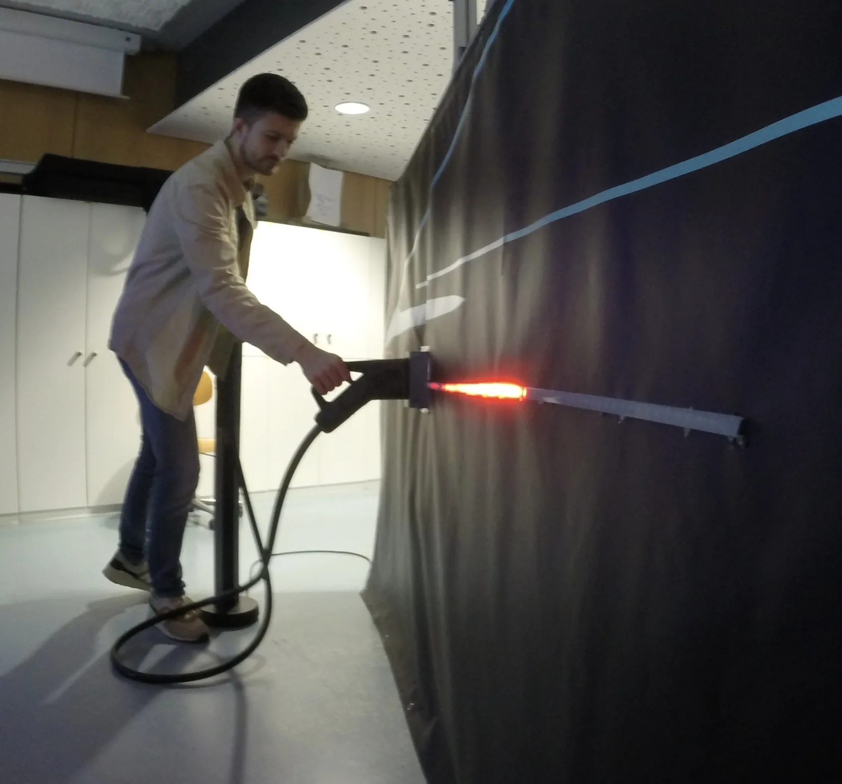 Testperson steckt im Mobile Lab den Ladestecker ein, die Lichtleiste leuchtet rot